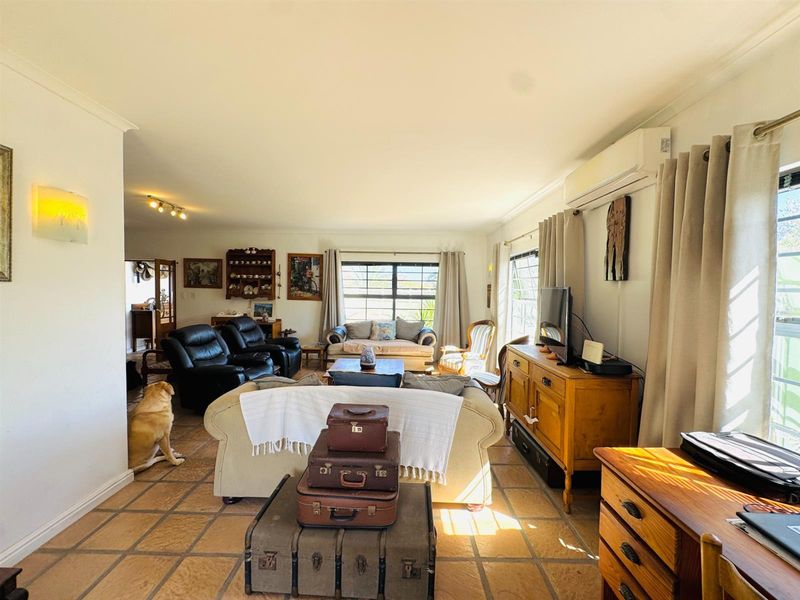 Spacious living room featuring tiled flooring, coving, and a wall-mounted split-system air conditioner, offering a comfortable and functional layout.