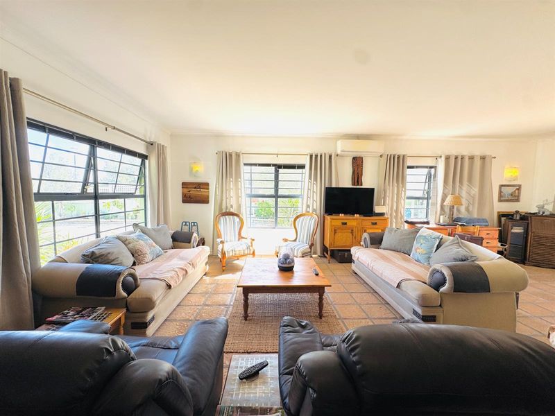 Spacious living room featuring tiled flooring, split-system air conditioning, and large windows that provide ample natural light.