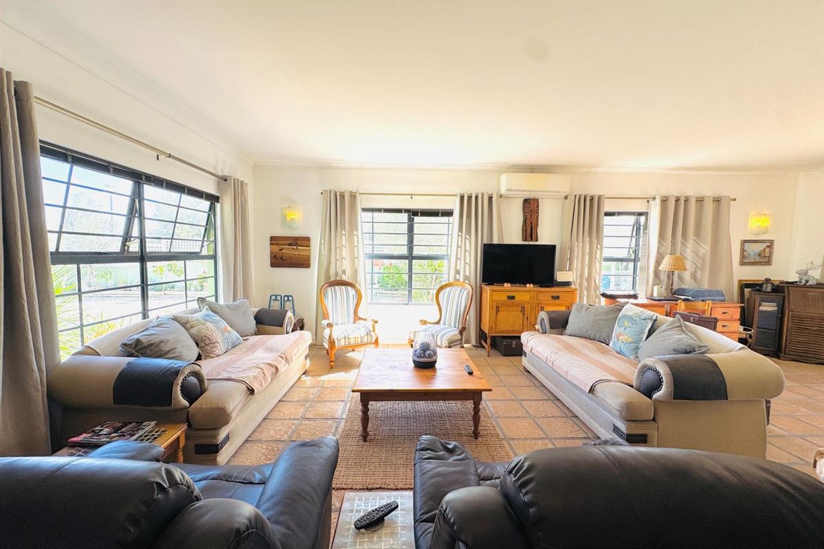 Spacious living room featuring tiled flooring, split-system air conditioning, and large windows that provide ample natural light.