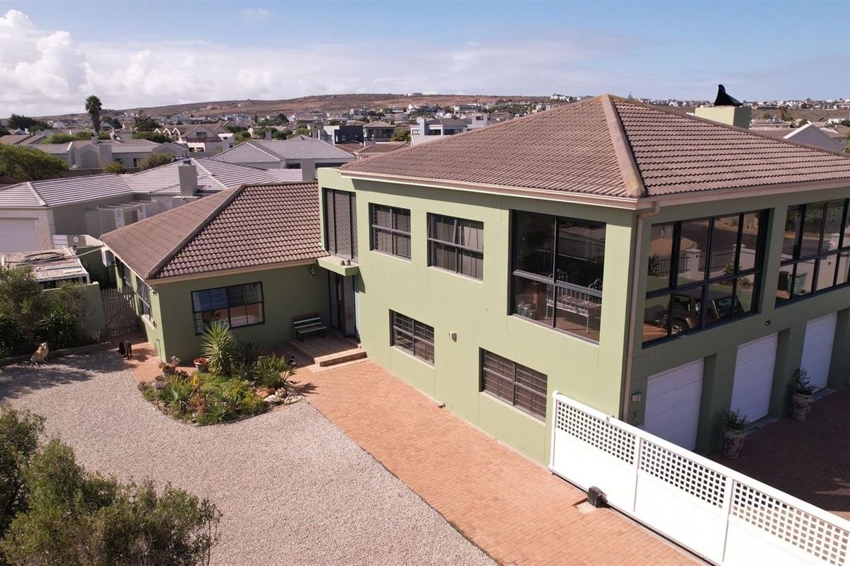Aerial view of a two-story residential property featuring a tiled roof, paved driveway, and integrated garage doors in a suburban setting.