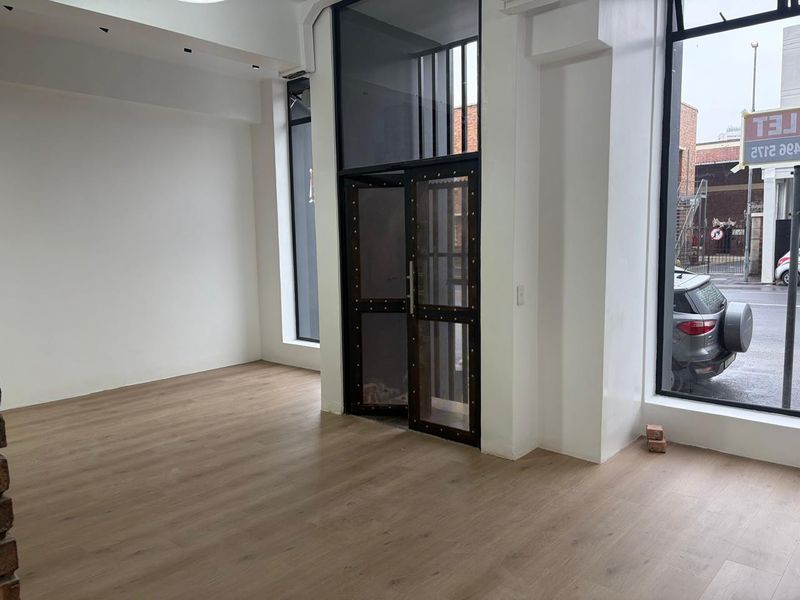 Bright open-plan retail space featuring modern wood-look flooring, high ceilings, and large glass windows providing excellent street-level visibility and natural light.