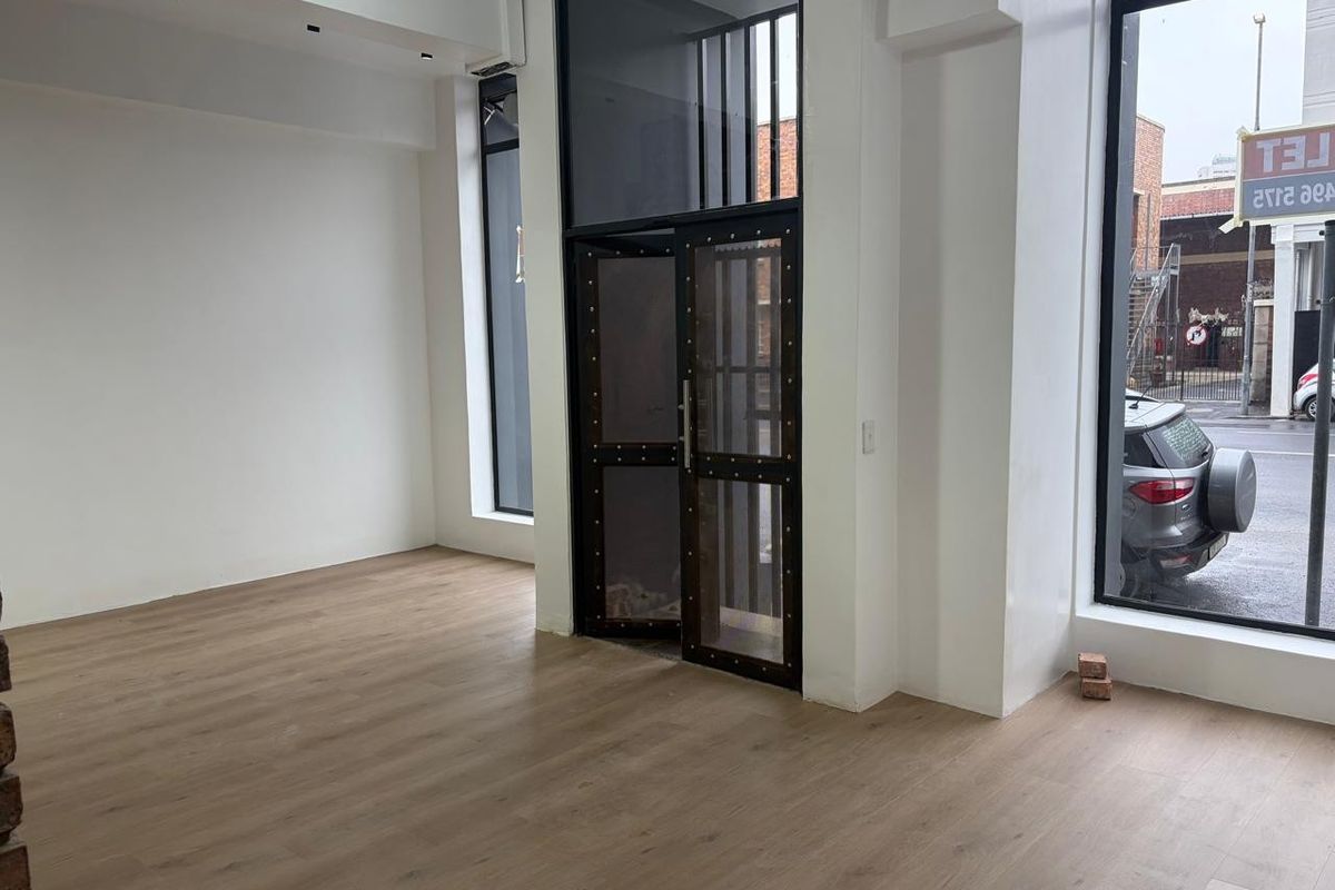 Bright open-plan retail space featuring modern wood-look flooring, high ceilings, and large glass windows providing excellent street-level visibility and natural light.