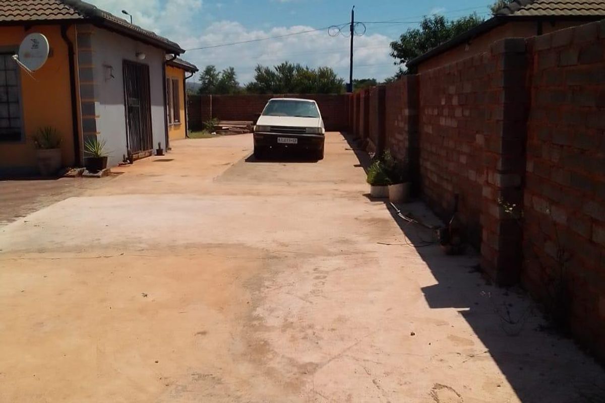 A view of the side driveway and exterior area featuring a concrete surface and brick boundary wall alongside the main dwelling structure.