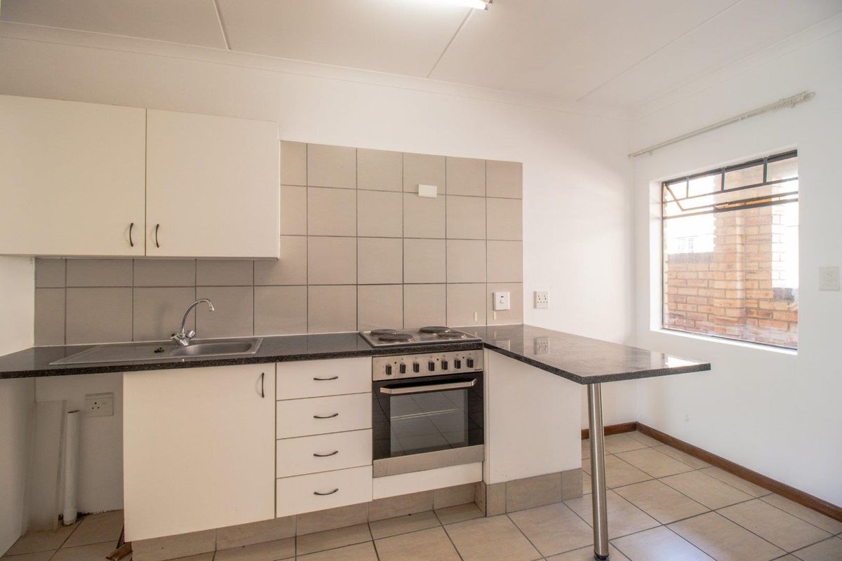 A functional kitchen featuring white cabinetry, granite countertops, a built-in oven and hob, and a convenient breakfast bar area.