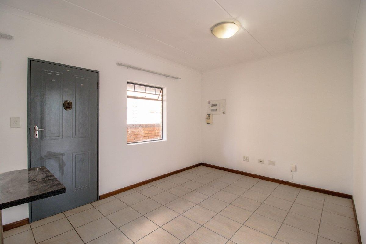 A clean, empty living area featuring neutral tiled flooring, white walls, and a functional layout ready for personalization.