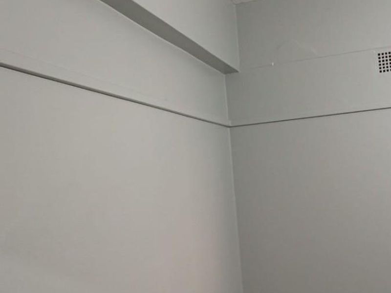 A vacant room featuring neutral painted walls, a structural bulkhead, and worn flooring, offering a blank canvas for renovation or interior design.