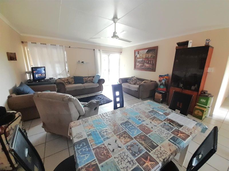 Open plan living and dining area featuring tiled flooring, a ceiling fan, and sliding glass door access to the exterior.