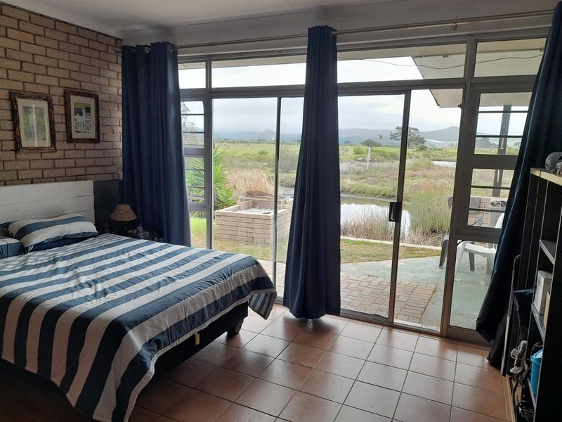 Bedroom featuring exposed brick wall, tiled flooring, and large sliding glass doors providing direct access to the outdoor patio and scenic views.