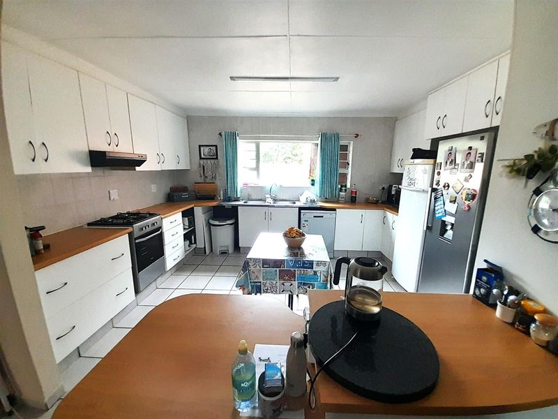 Functional kitchen featuring white cabinetry, laminate countertops, gas stove, and tiled flooring, offering a practical layout with ample storage space.