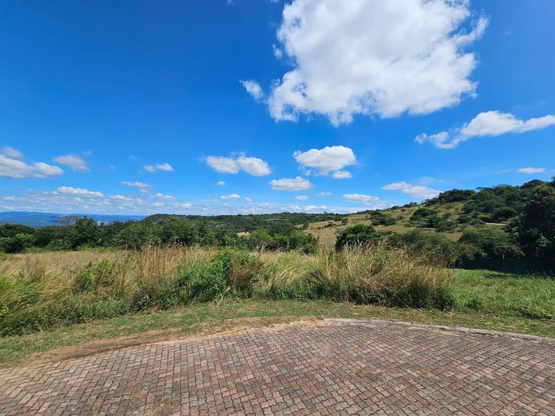 A scenic view of the natural landscape and rolling hills from a paved driveway area on the residential vacant land property.