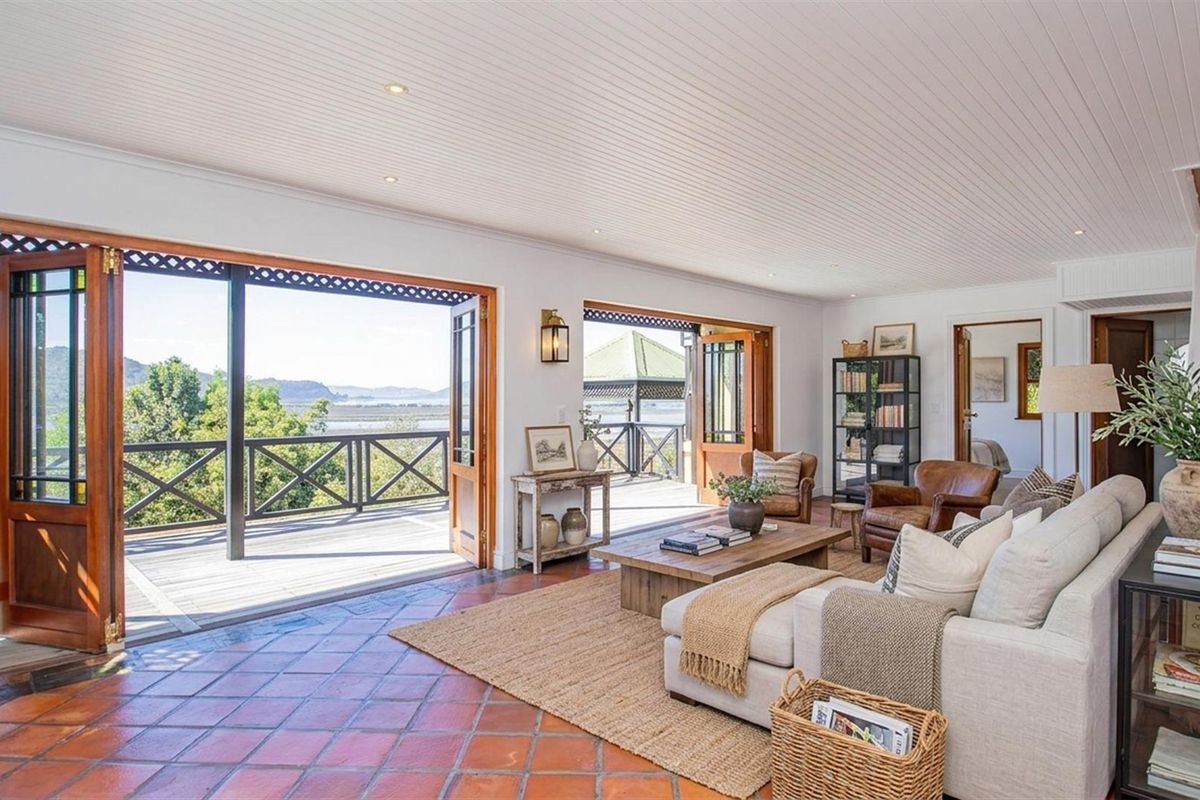 Spacious living area featuring terracotta tile flooring, timber-framed bi-fold doors opening onto a scenic deck, and recessed ceiling lighting.