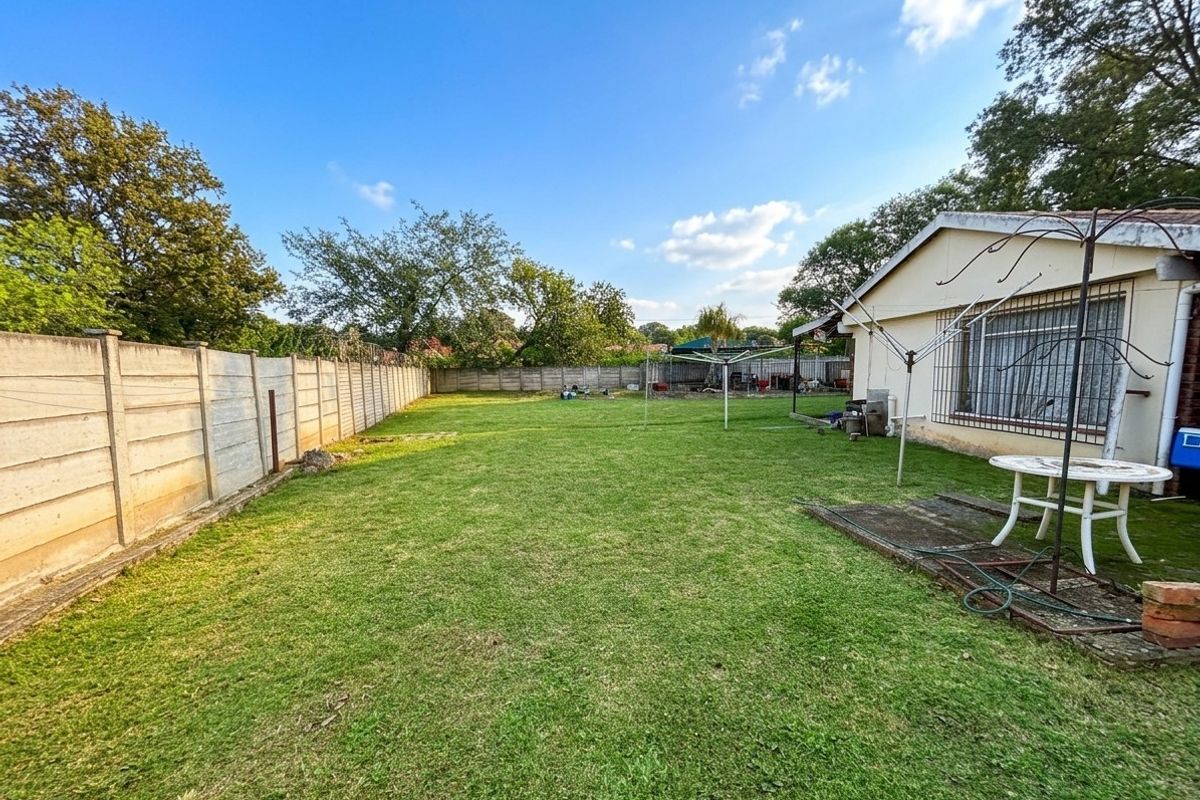 A spacious rear garden featuring a large lawn area, perimeter precast concrete walling, and direct access to the main dwelling.
