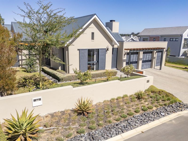 A well-maintained modern house featuring a metal roof, triple garage, and landscaped front garden with a perimeter wall and timber pergola.