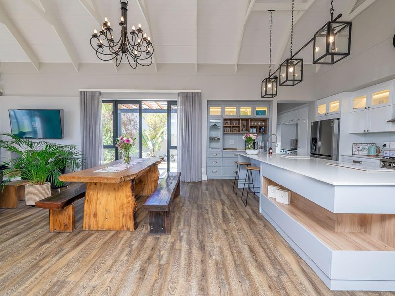 Spacious open-plan living and kitchen area featuring vaulted ceilings, modern cabinetry, a large kitchen island, and seamless access to the outdoor patio.