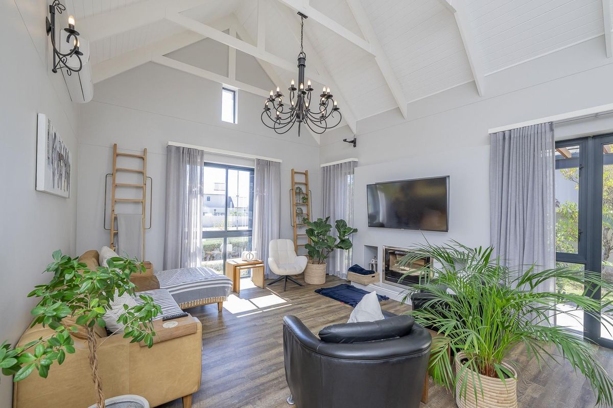Spacious living room featuring a high vaulted ceiling with exposed trusses, a built-in fireplace, and modern laminate flooring, creating a bright and airy atmosphere.