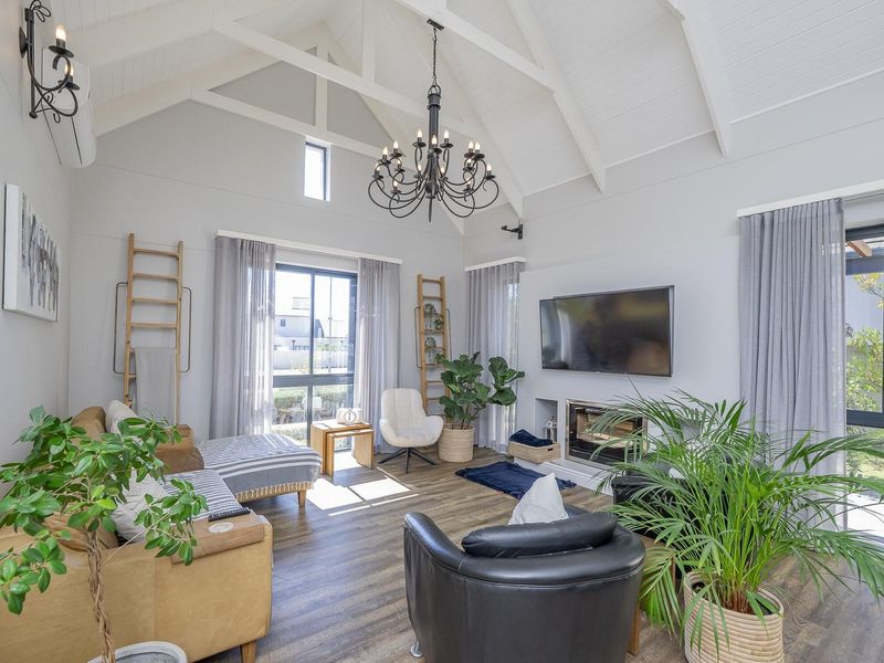 Spacious living room featuring a high vaulted ceiling with exposed trusses, a built-in fireplace, and modern laminate flooring, creating a bright and airy atmosphere.