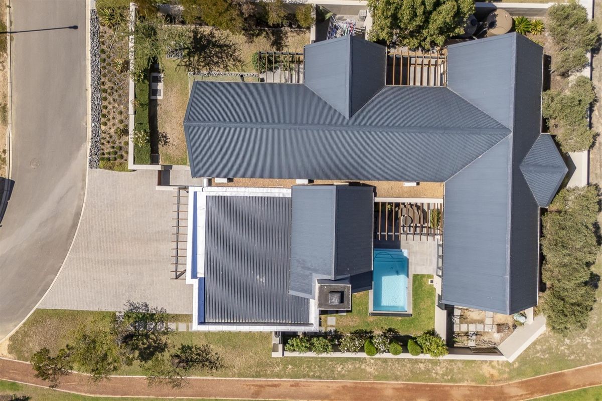 Aerial view of the property showcasing the roof structure, swimming pool, landscaped garden, and paved driveway area.