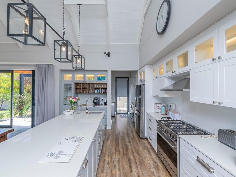 Modern, well-appointed kitchen featuring a large central island, high-end gas range, vaulted ceilings, and seamless access to the outdoor patio area.