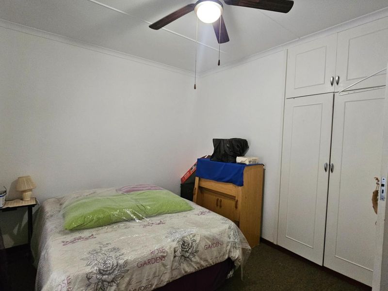 A bedroom featuring built-in cupboards and a ceiling fan, providing functional storage and overhead lighting.