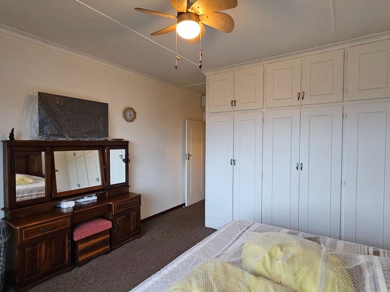 A bedroom featuring extensive built-in floor-to-ceiling cabinetry and a ceiling fan, providing ample storage space.