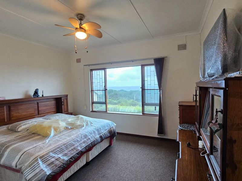 A spacious bedroom featuring a ceiling fan, large windows with scenic views, and carpeted flooring.
