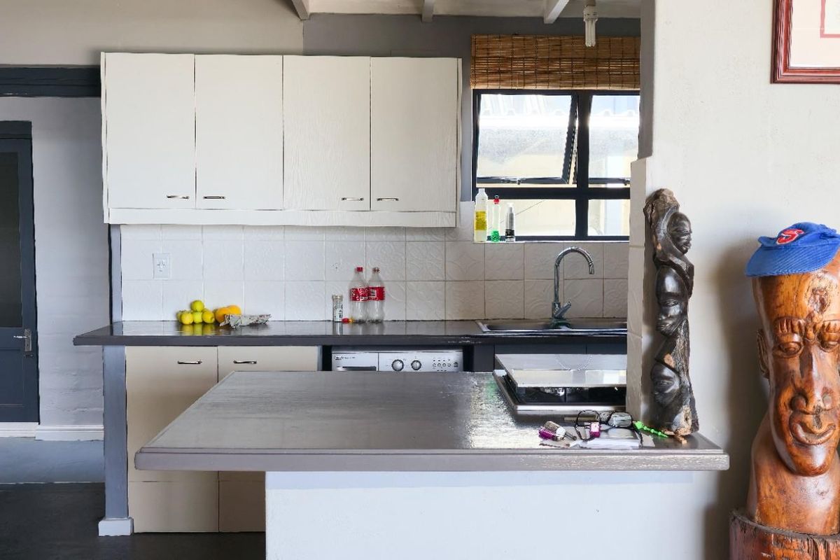 A functional kitchen area featuring built-in cabinetry, a dark countertop, a stainless steel sink, and a breakfast bar counter.