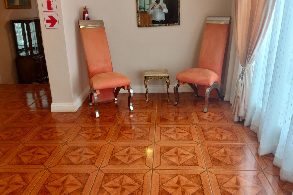 A bright interior space featuring decorative patterned floor tiles, neutral wall finishes, and floor-to-ceiling curtains leading to an outdoor area.