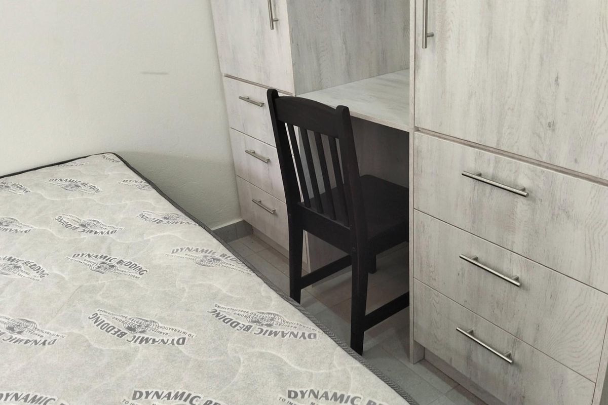 A bedroom featuring built-in light wood-grain cabinetry with integrated desk space and drawers.