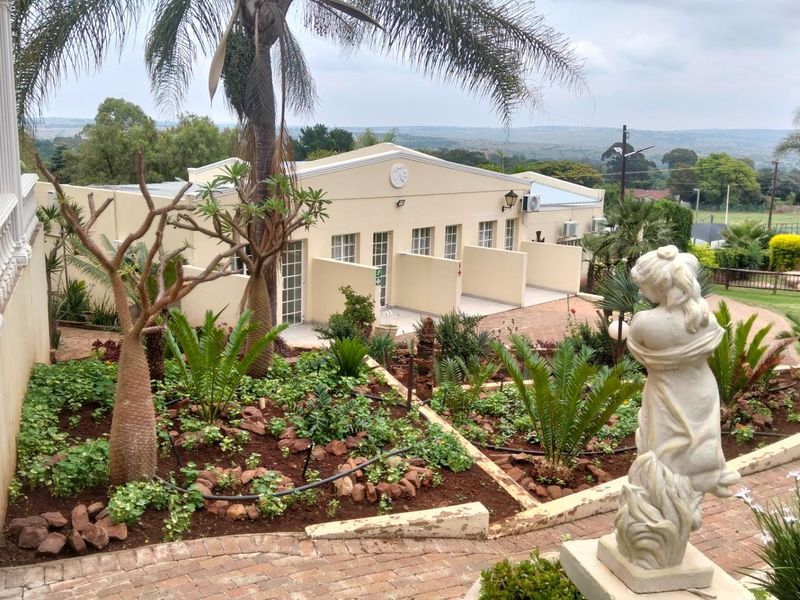 A view of the landscaped garden and courtyard area featuring paved pathways, established plantings, and a well-maintained exterior building facade.