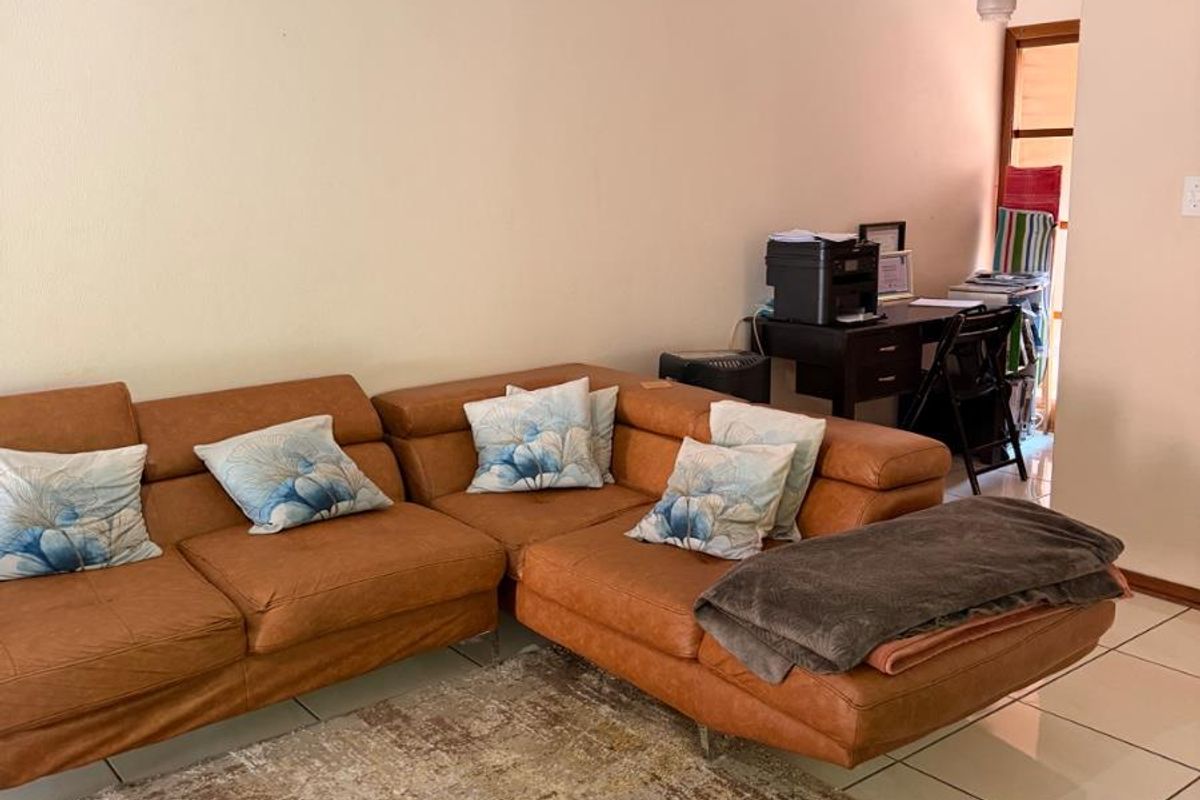 A living room area featuring tiled flooring and a neutral wall finish, providing a functional space for relaxation.