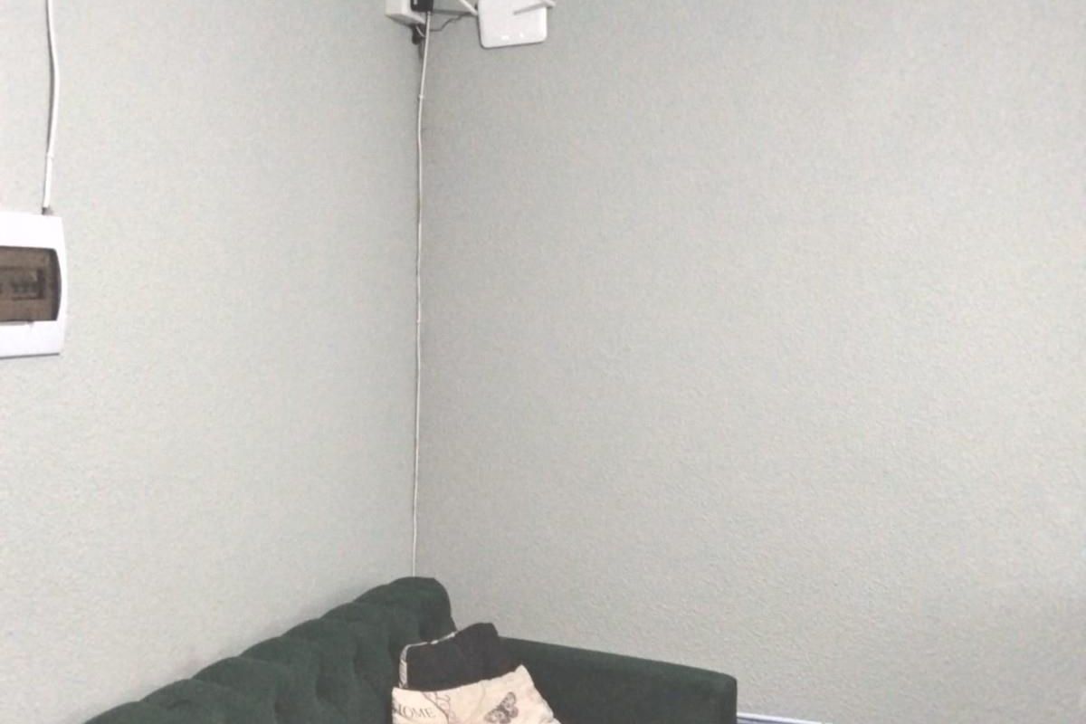 A living room corner featuring decorative ceiling cornicing, an electrical distribution board, and visible surface-mounted wiring along the wall.