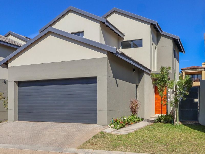 Modern double-story townhouse featuring a paved driveway, integrated double garage, and a welcoming front entrance.