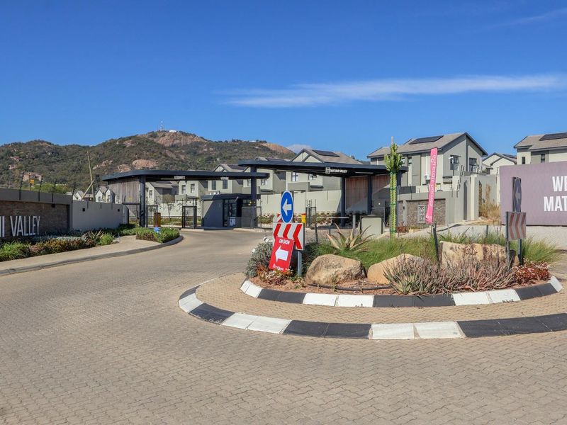 Entrance view of Matumi Valley estate featuring a paved traffic circle, security gatehouse, and clear signage.