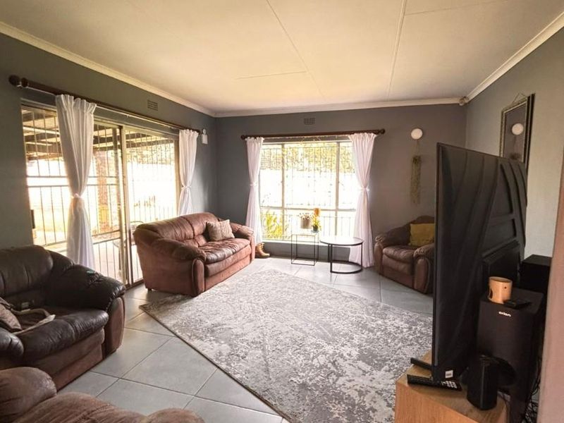 Spacious living room featuring large windows, tiled flooring, and sliding door access to the exterior, providing ample natural light.