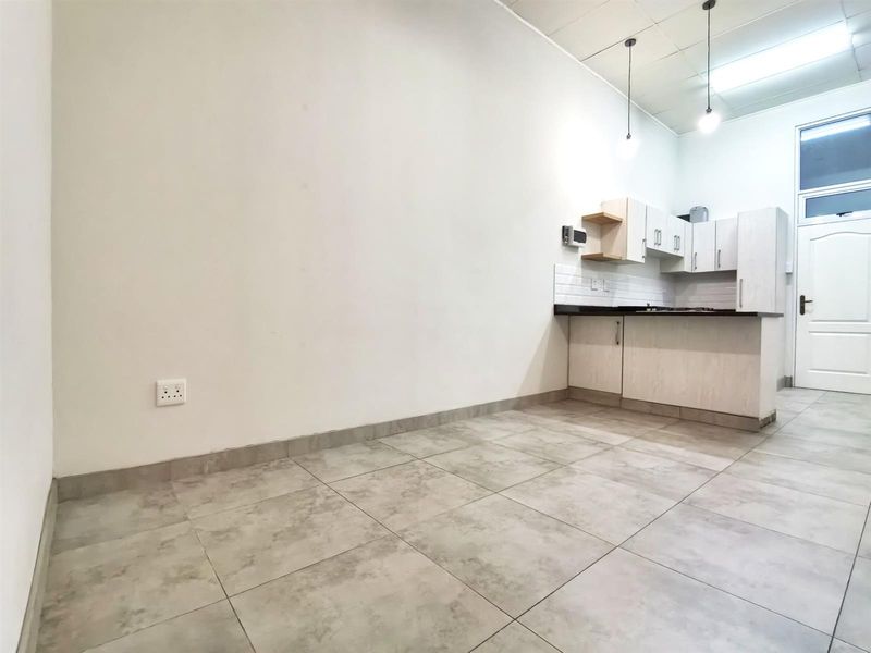 An open-plan kitchen area featuring tiled flooring, modern cabinetry, and a compact layout, presenting a clean canvas for potential interior design updates.