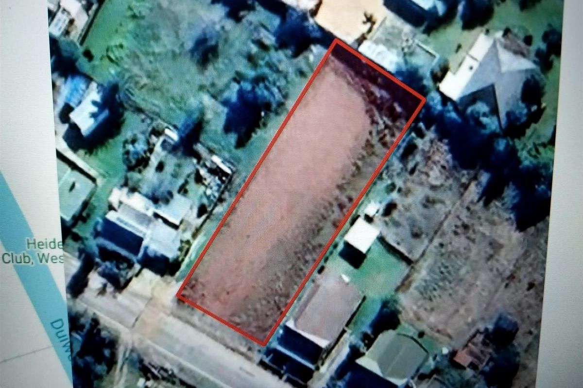 An aerial view of a vacant residential plot outlined in red, situated within an established neighborhood.