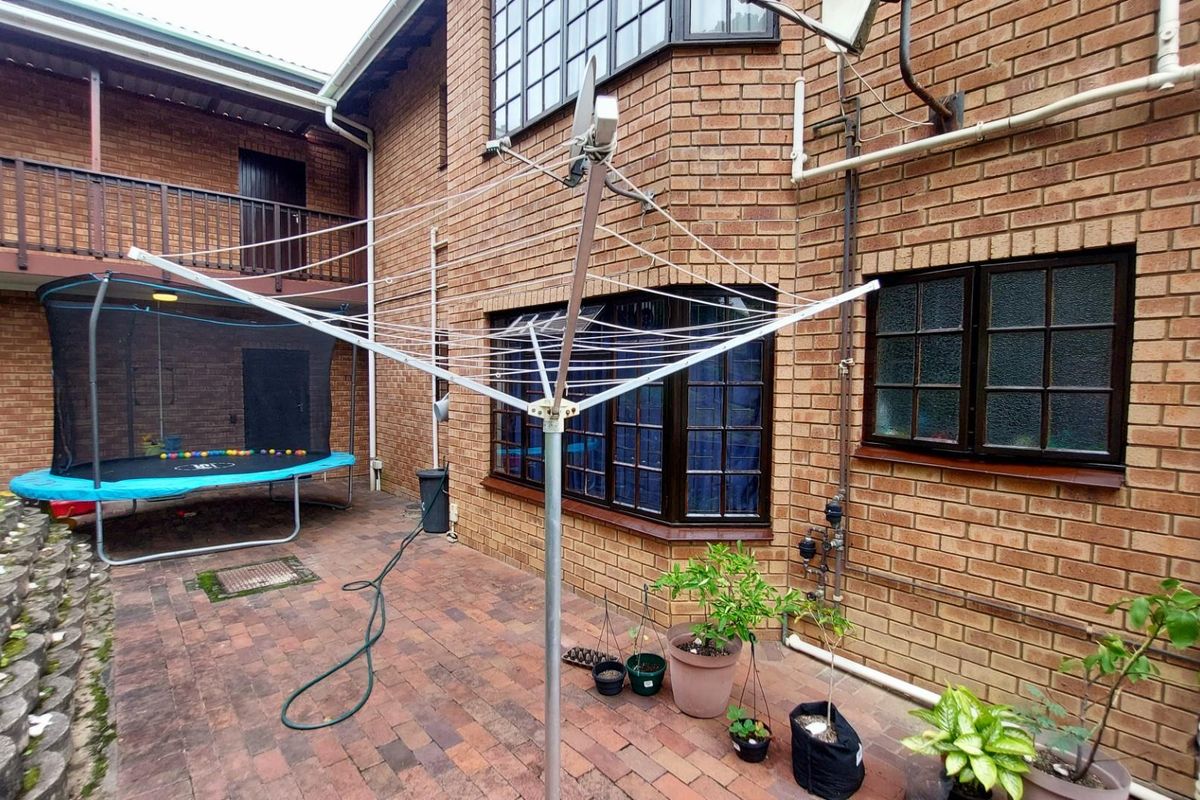 A rear courtyard area featuring brick paving, a rotary clothesline, and access to the building's exterior facade with timber-framed windows.