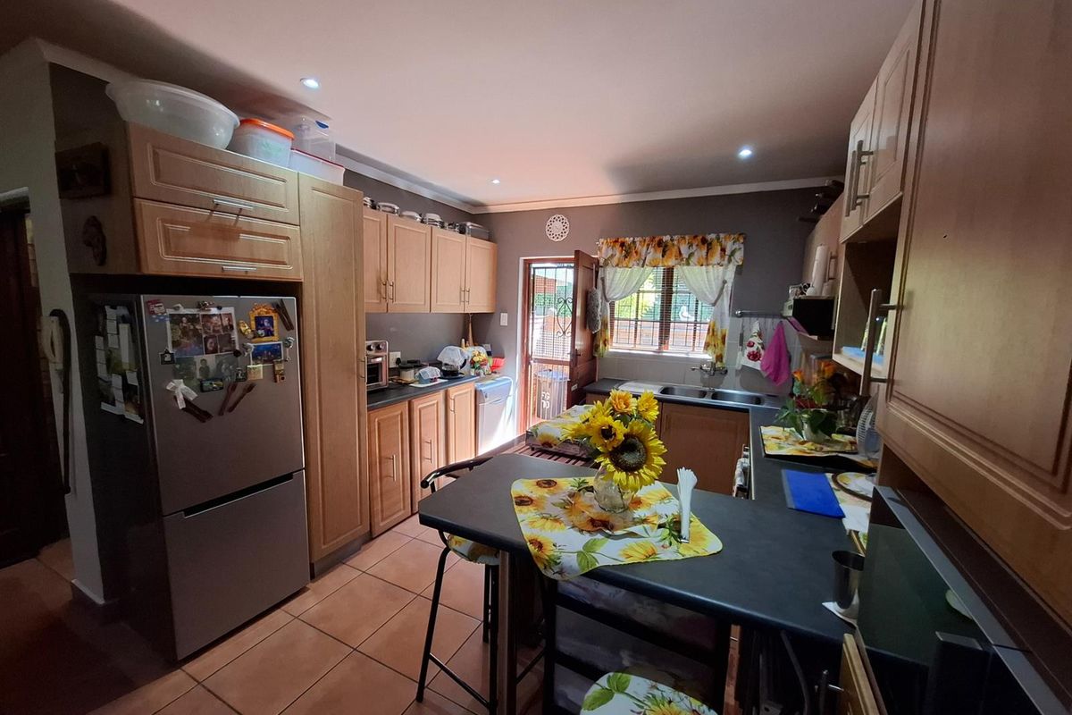 A functional kitchen featuring wooden cabinetry, dark countertops, tiled flooring, and a breakfast nook, with direct access to the exterior.