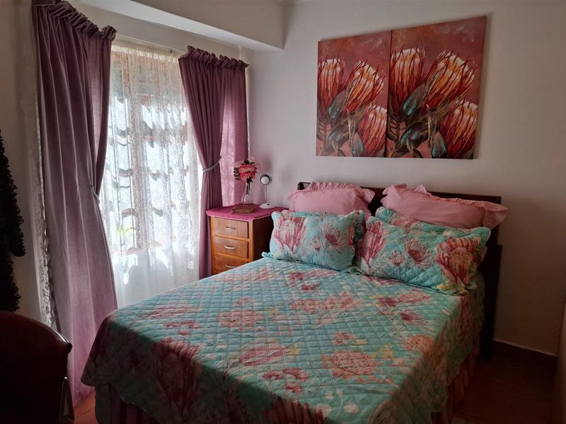 A cozy bedroom featuring tiled flooring and a window with curtain treatments, providing a comfortable and functional sleeping space.