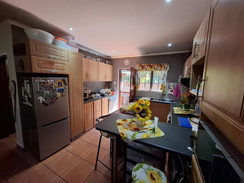 A functional kitchen featuring wooden cabinetry, dark countertops, tiled flooring, and a breakfast nook, with direct access to the exterior.
