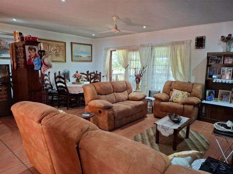 Spacious open-plan living and dining area featuring tiled flooring, recessed ceiling lighting, and direct access to an outdoor patio through glass doors.