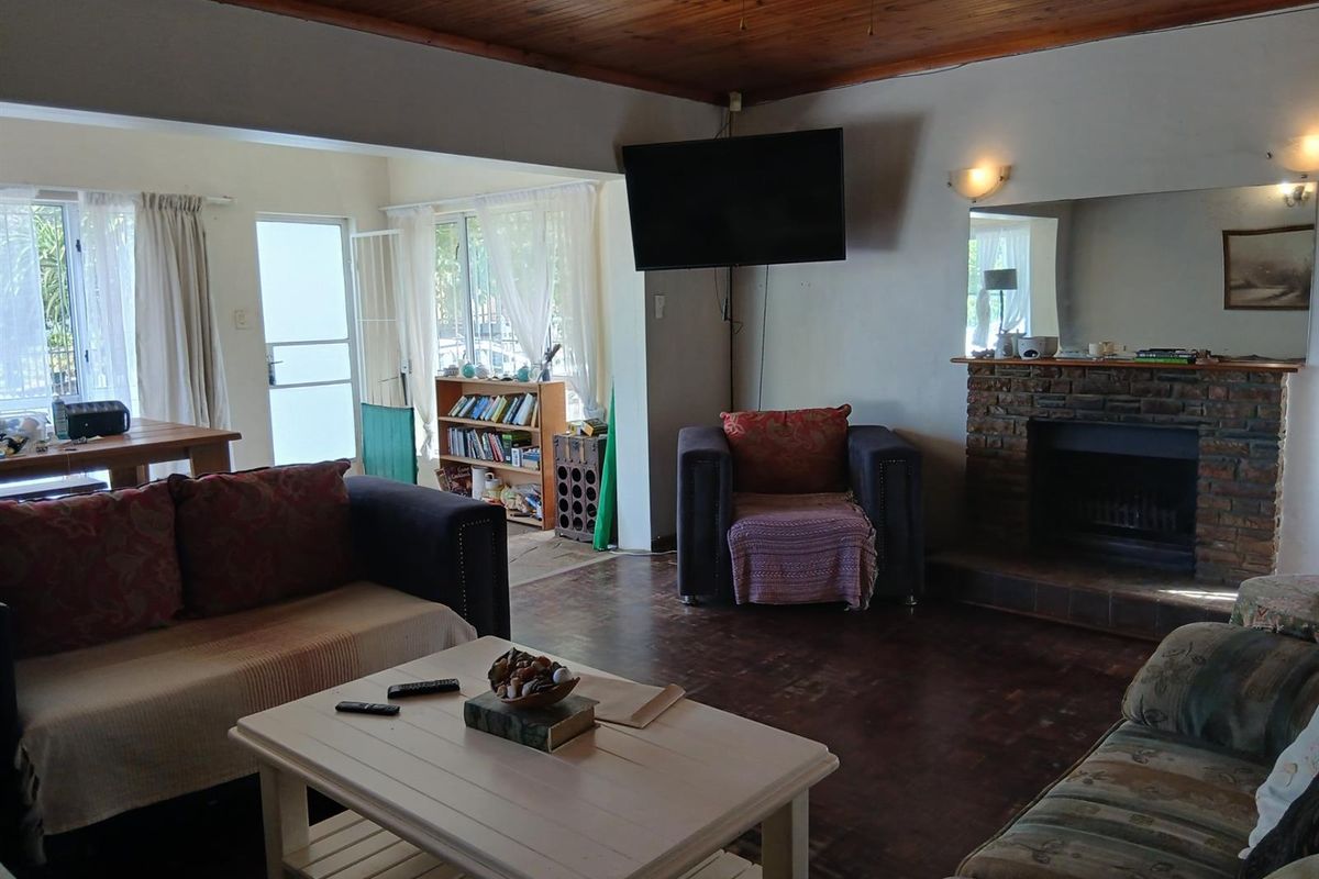Spacious living area featuring a brick fireplace, timber ceiling, and direct access to the outdoor patio area.