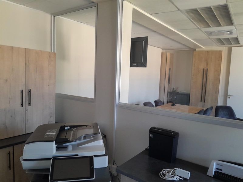 A functional office space featuring built-in cabinetry, a glass partition wall, and a suspended ceiling, providing a professional and organized work environment.
