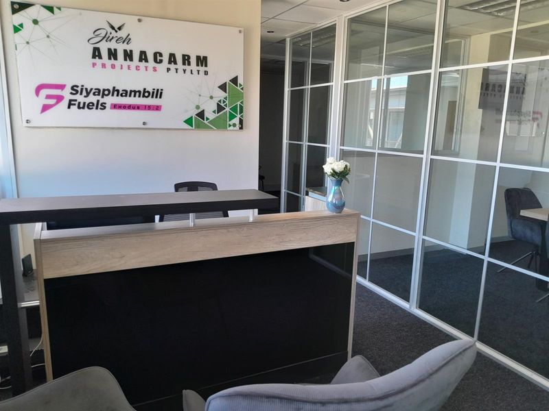 Professional office reception area featuring a modern reception desk, glass partition walls, and carpeted flooring.