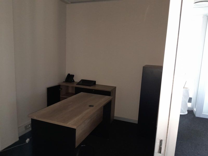 A compact office space featuring neutral walls, carpeted flooring, and built-in electrical infrastructure, suitable for a private workspace.