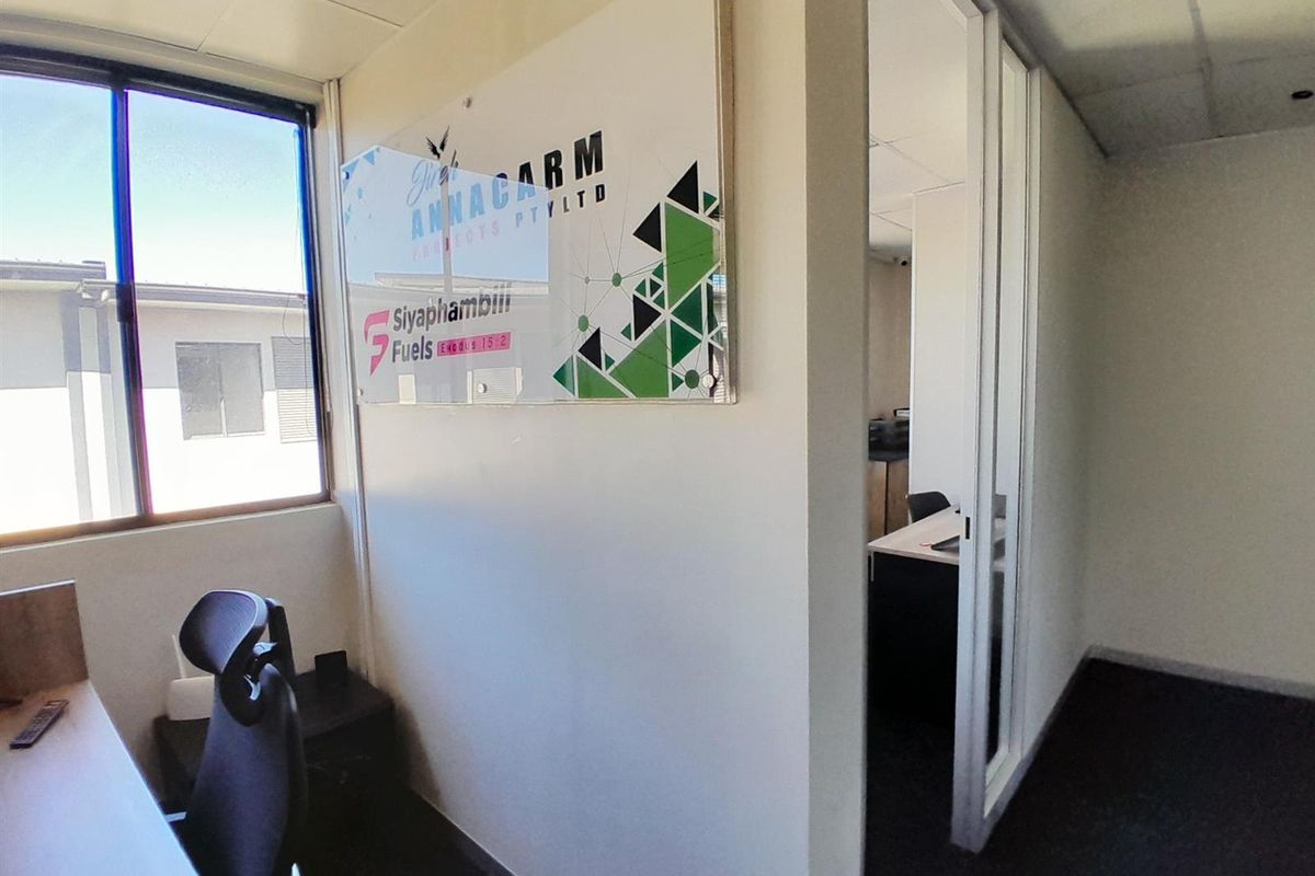 A professional office space featuring a glass partition door, suspended ceiling, and large windows providing natural light.