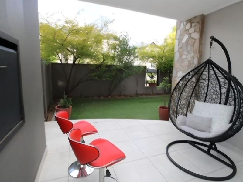 Covered patio area featuring a built-in braai, stone cladding accent wall, and tiled flooring, overlooking a private garden space.