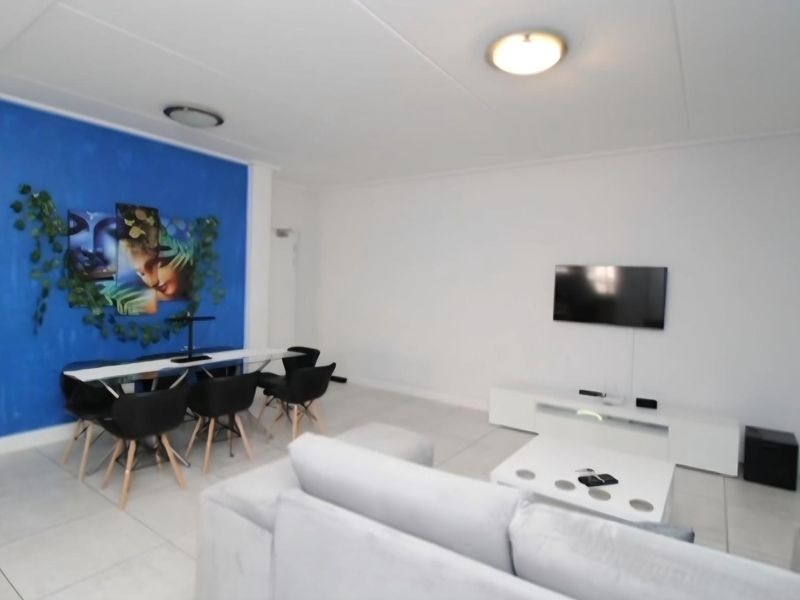 Spacious living area featuring neutral tiled flooring and a bright blue accent wall, providing a versatile space for relaxation and dining.