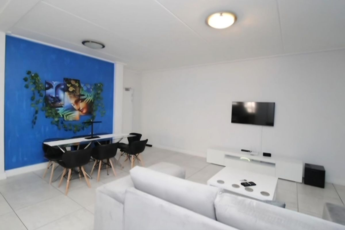 Spacious living area featuring neutral tiled flooring and a bright blue accent wall, providing a versatile space for relaxation and dining.