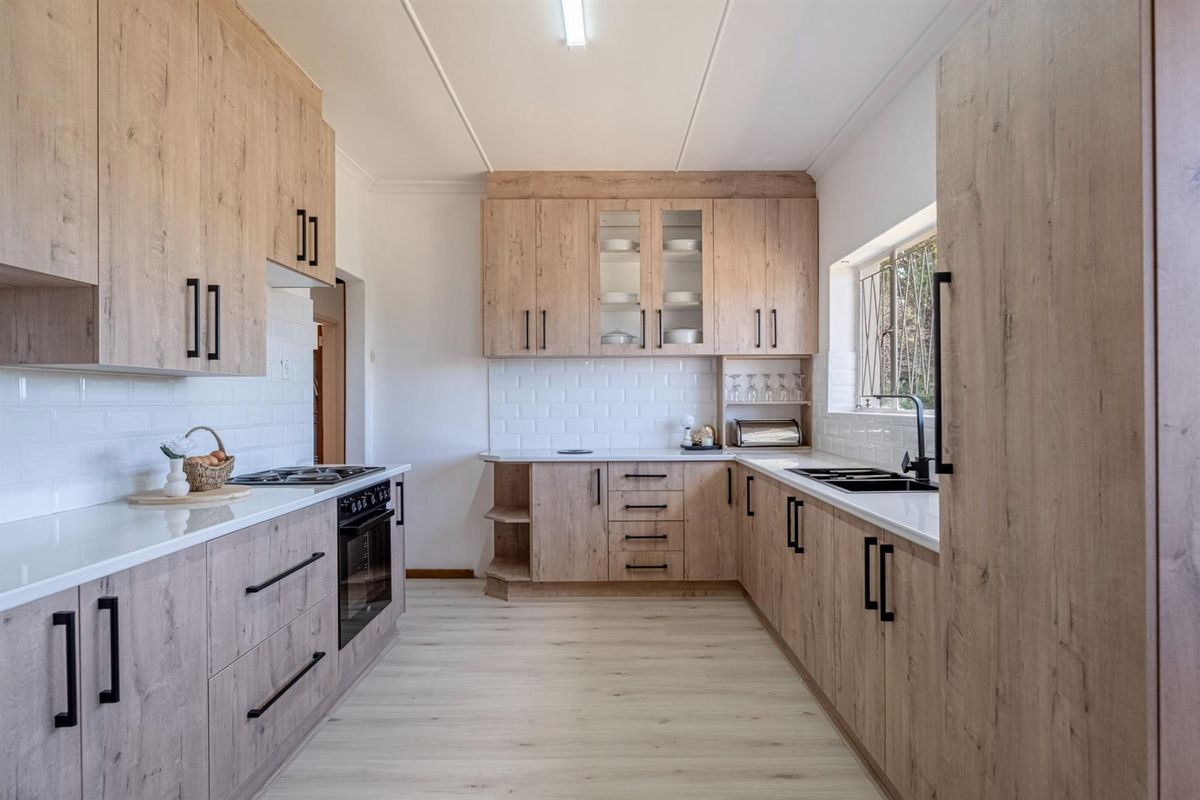 Modern kitchen featuring light wood-grain cabinetry, white subway tile backsplash, stone countertops, and integrated appliances with a clean, contemporary finish.